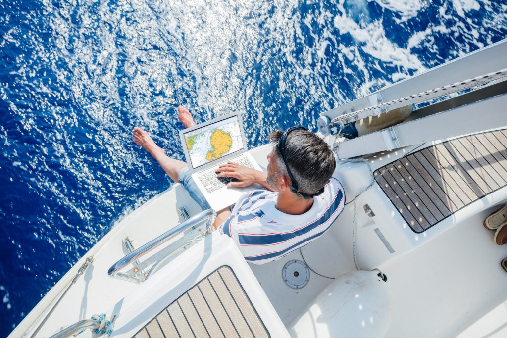 Young and handsome man with laptop computer on sailboat